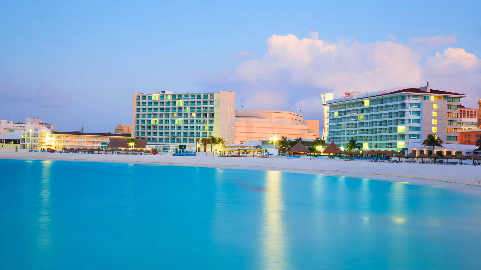 Krystal Cancun resort at sunset with a beach view and hotel buildings in the background.