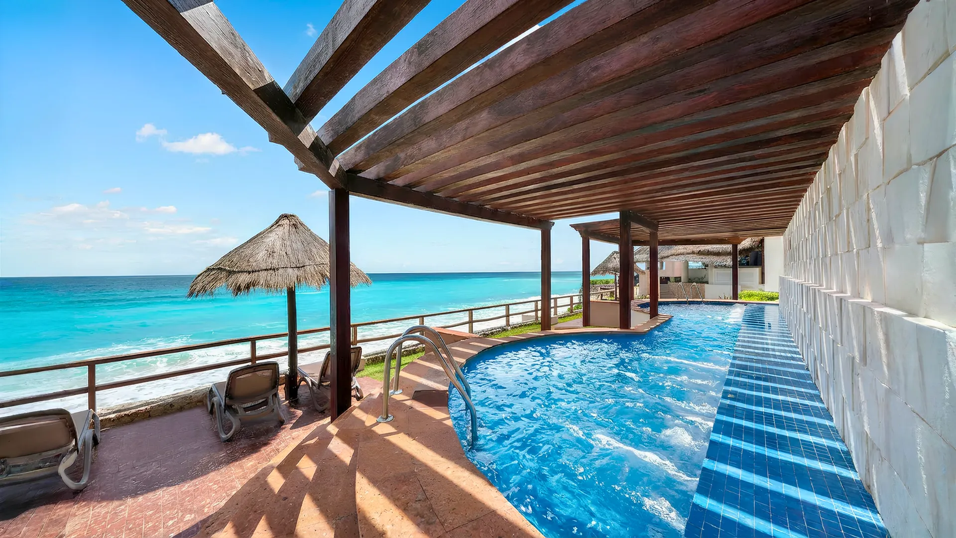 Oceanfront pool at Royal Solaris Cancun with wooden pergola, turquoise water, and panoramic view of the Caribbean Sea.