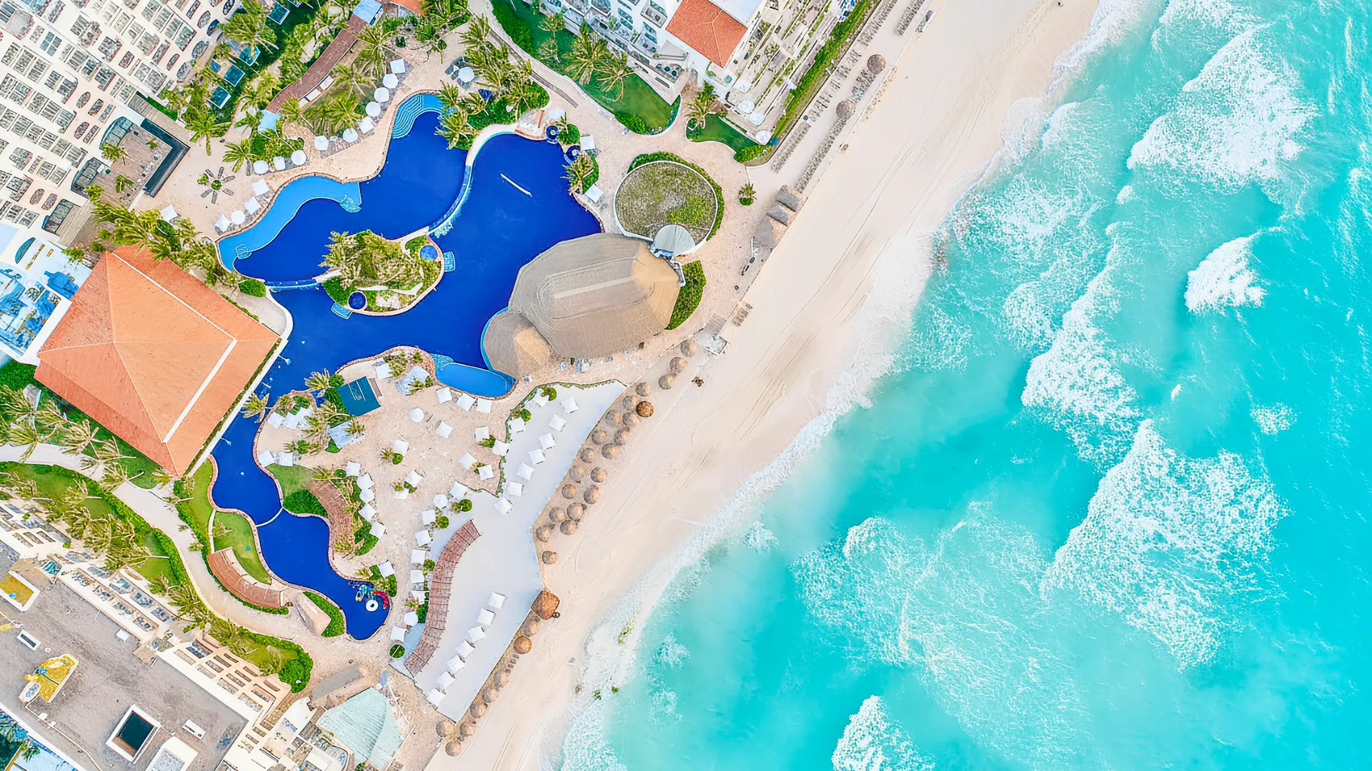 Aerial view of Fiesta Americana Cancun showing the resort’s lagoon-style pool, white sandy beach, and turquoise Caribbean Sea.