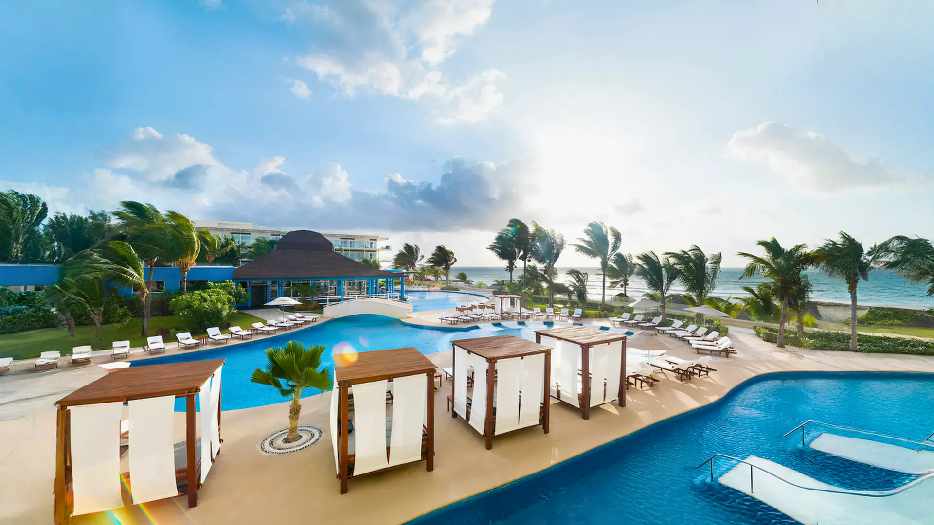 Aerial view of pools, cabanas, and beachfront area at Azul Beach Resort Riviera Cancun during sunset.