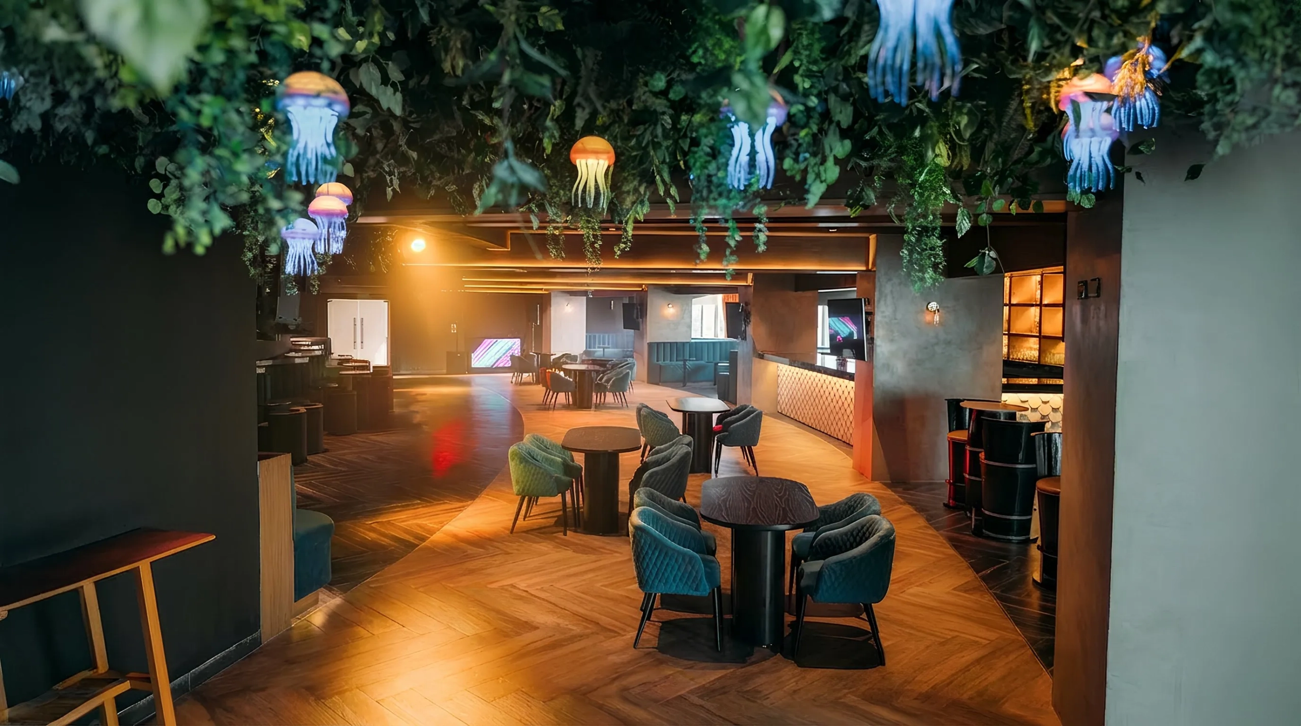 Stylish indoor restaurant and lounge at Seadust Cancun with hanging jellyfish lights, greenery ceiling decor, and cozy seating.