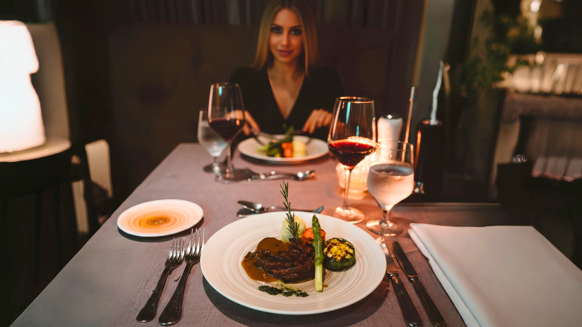 Woman dining on steak and vegetables with red wine at Hard Rock Cancun restaurant.