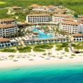 Aerial view of Secrets Playa Mujeres Golf & Spa Resort in Cancun, featuring beachfront suites, turquoise waters, and lush greenery.