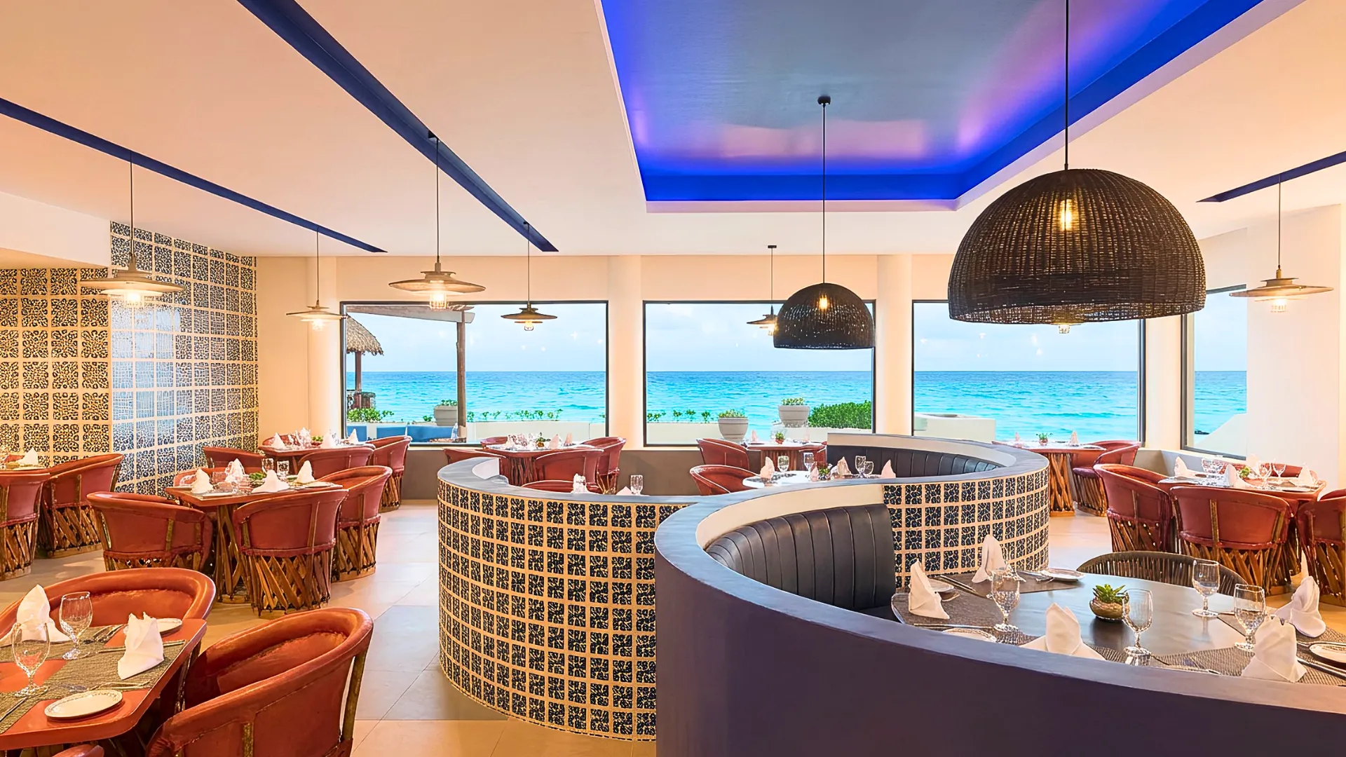 Elegant restaurant at GR Solaris Cancun with ocean views, modern lighting, and colorful seating arrangements.