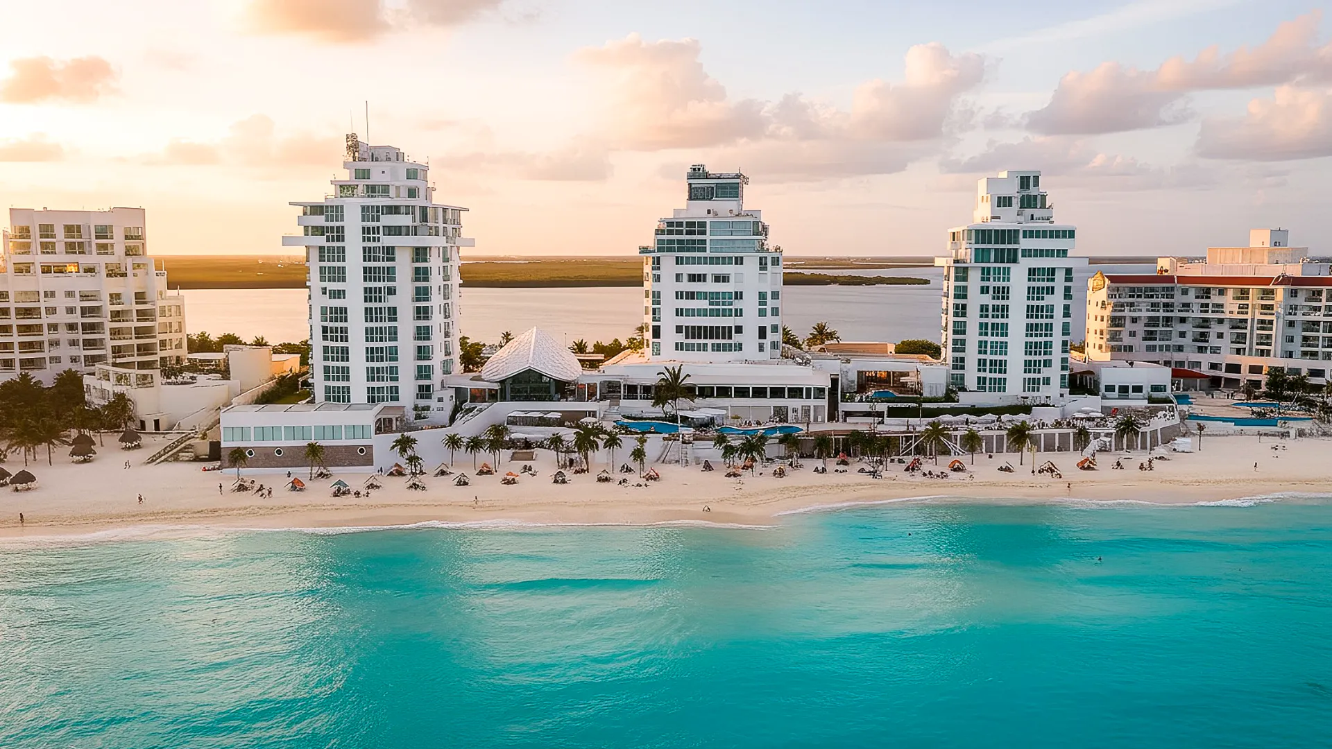 Stunning view of the beachfront with a resort building in the background at Óleo Cancun.