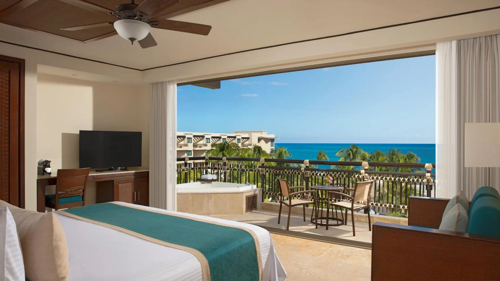 Luxury ocean-view suite at Dreams Riviera Cancun with whirlpool tub and furnished balcony overlooking the Caribbean Sea.