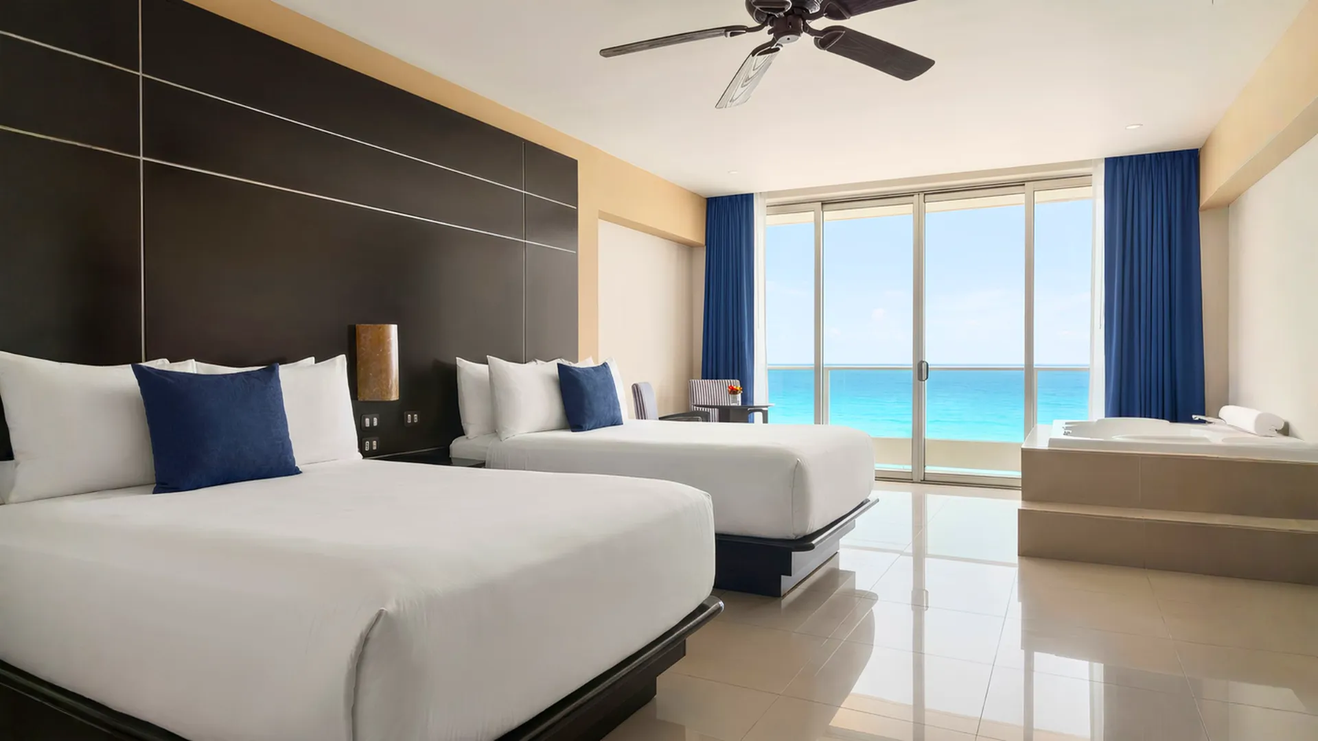 Modern double room at Seadust Cancun with ocean views, two beds, balcony, jacuzzi tub, and bright natural lighting.