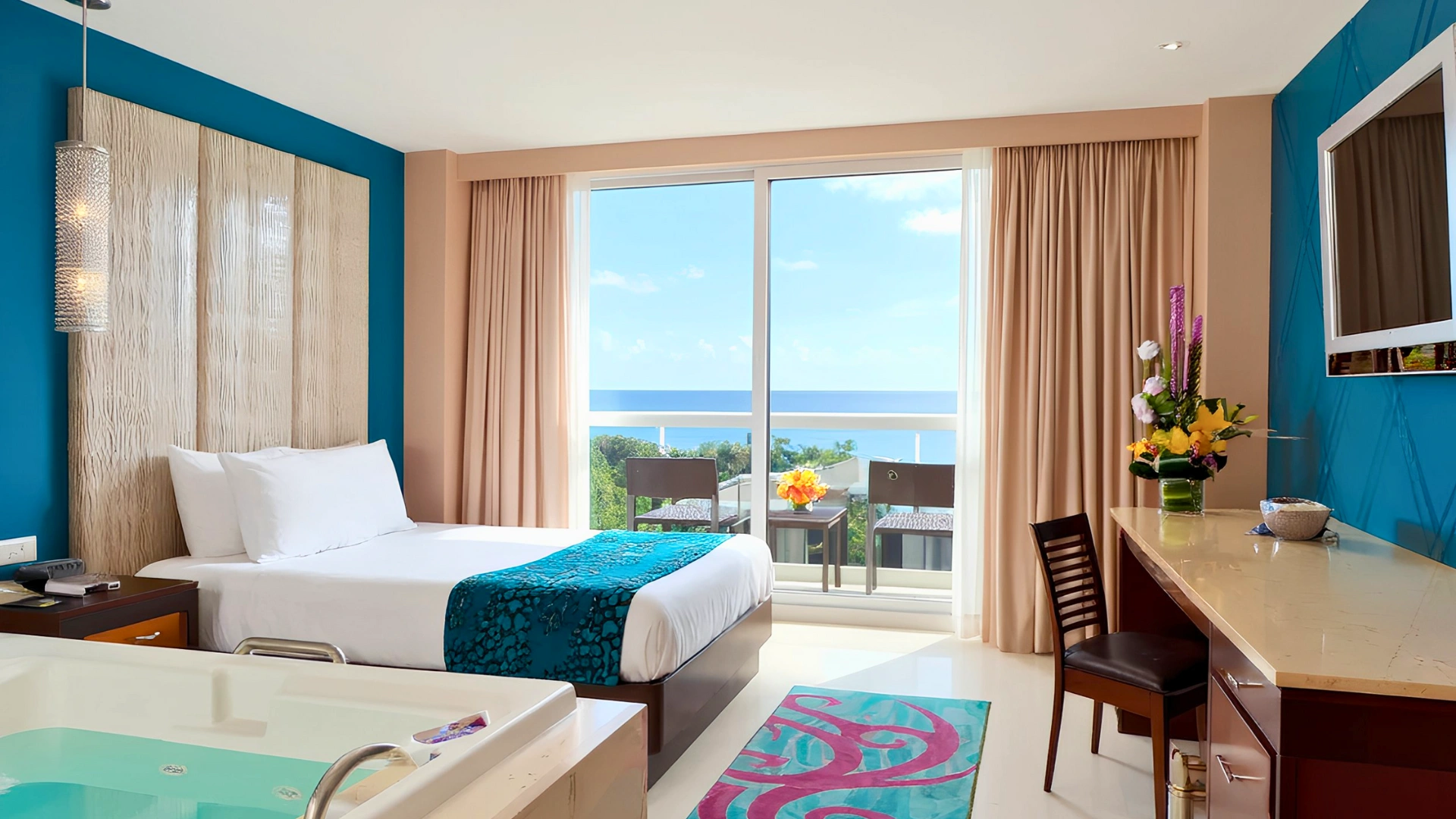  Ocean-view room at Hard Rock Cancun with a bed, desk, and large windows overlooking the sea.