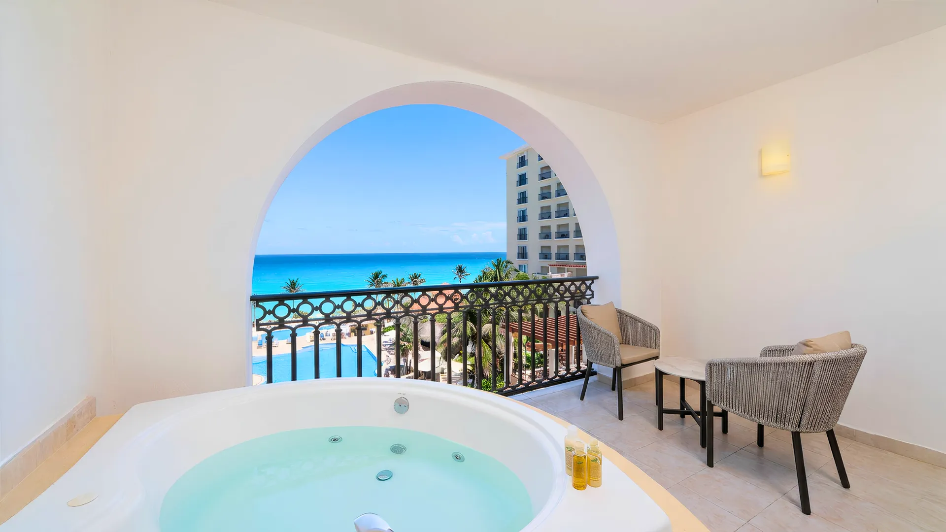 Jacuzzi terrace overlooking the ocean at GR Solaris Cancun, framed by an arched wall and balcony seating.