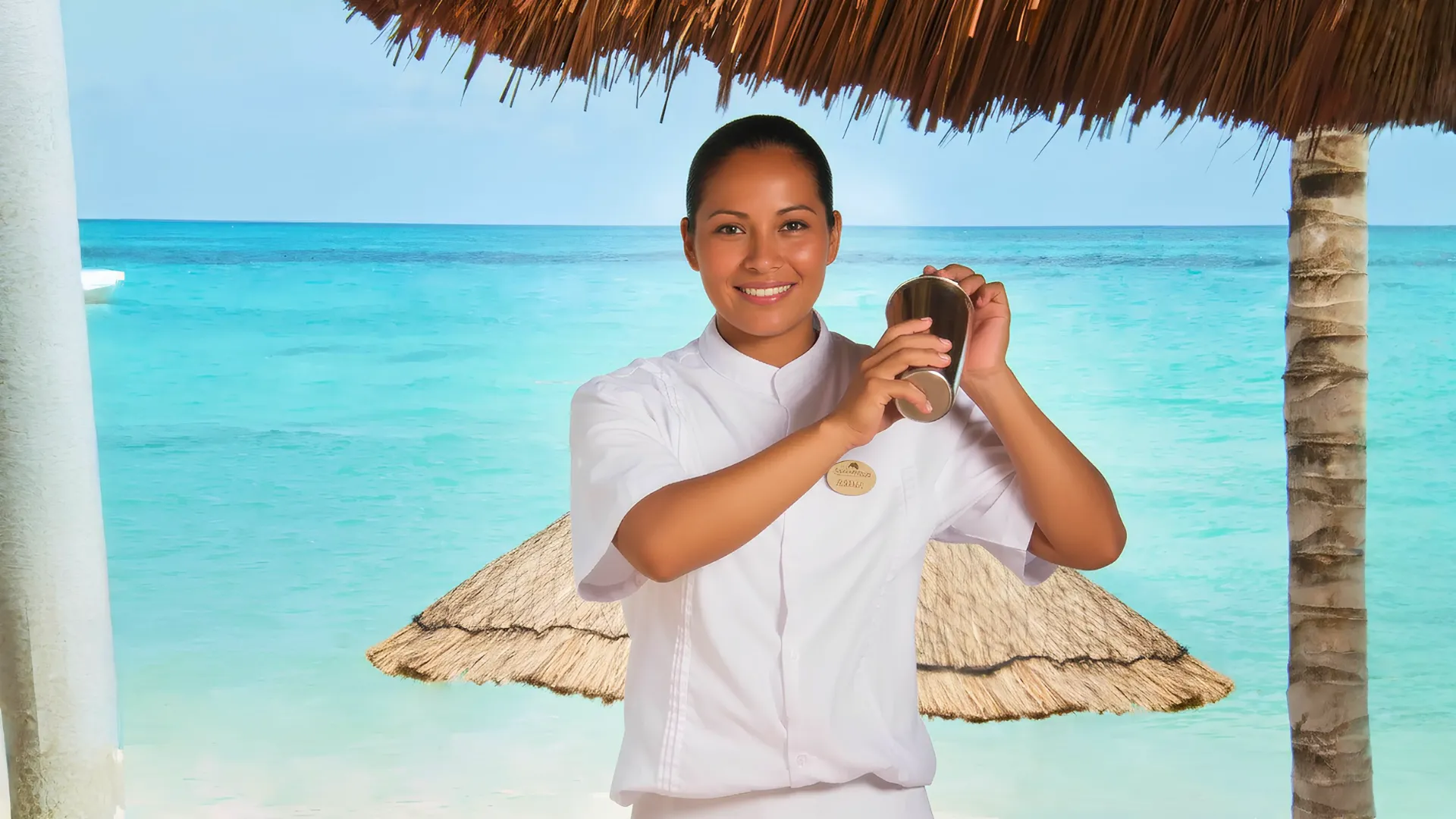 Resort staff member preparing a drink at Grand Fiesta Americana Coral Beach Cancun with a turquoise ocean backdrop.