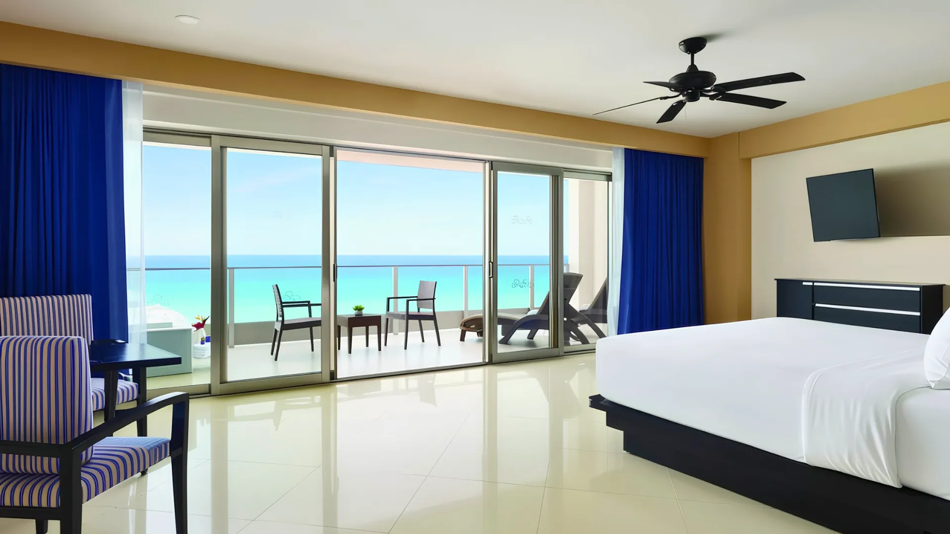 Spacious oceanview room at Seadust Cancun featuring a king bed, balcony seating, large sliding windows, and bright Caribbean Sea views.