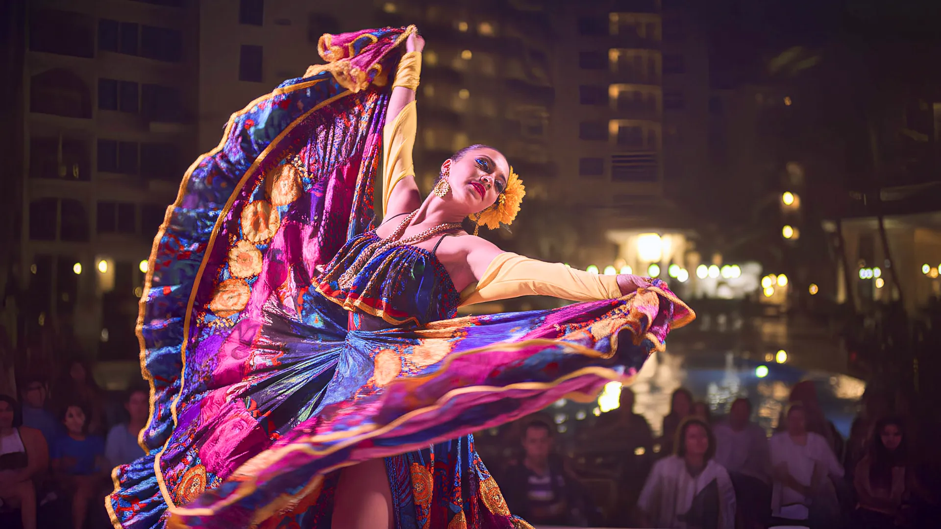 A dancer performing in vibrant attire during an outdoor evening performance at Occidental Costa Cancun.
