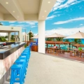 Open-air bar with blue stools overlooking the turquoise Caribbean Sea.