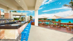 Open-air bar with blue stools overlooking the turquoise Caribbean Sea.