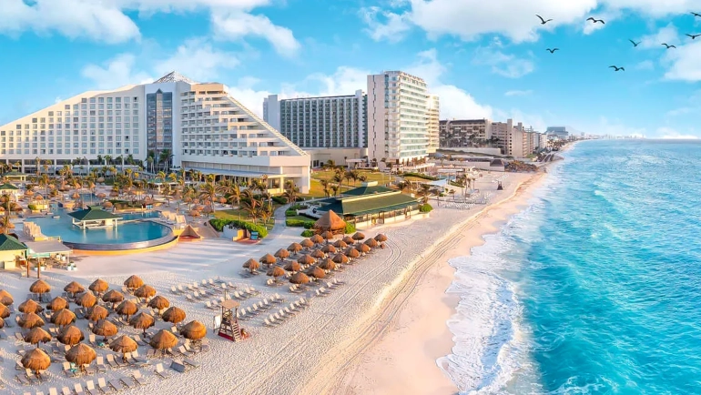 Aerial view of Garza Blanca Cancun resort with beachfront pools, sun loungers, and turquoise Caribbean Sea.