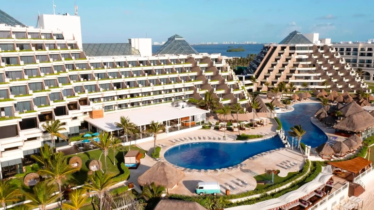 Aerial view of Paradisus Cancun resort with pyramid-style buildings, pools, and beachfront.