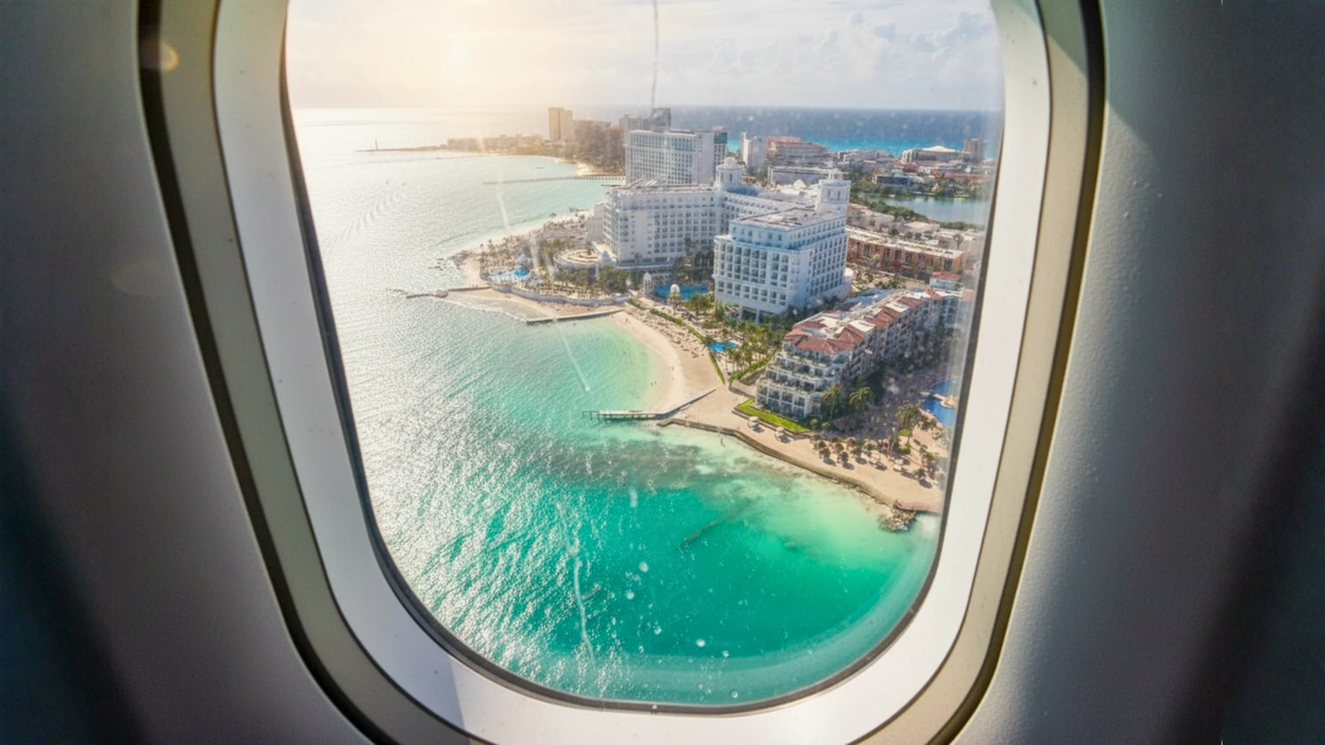 View of Cancun’s coastline and Hotel Zone seen through an airplane window during descent.