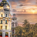 A creative blend showing Madrid’s historic Metropolis Building merging into a tropical Cancun beach sunset, symbolizing the journey from Spain to Mexico.