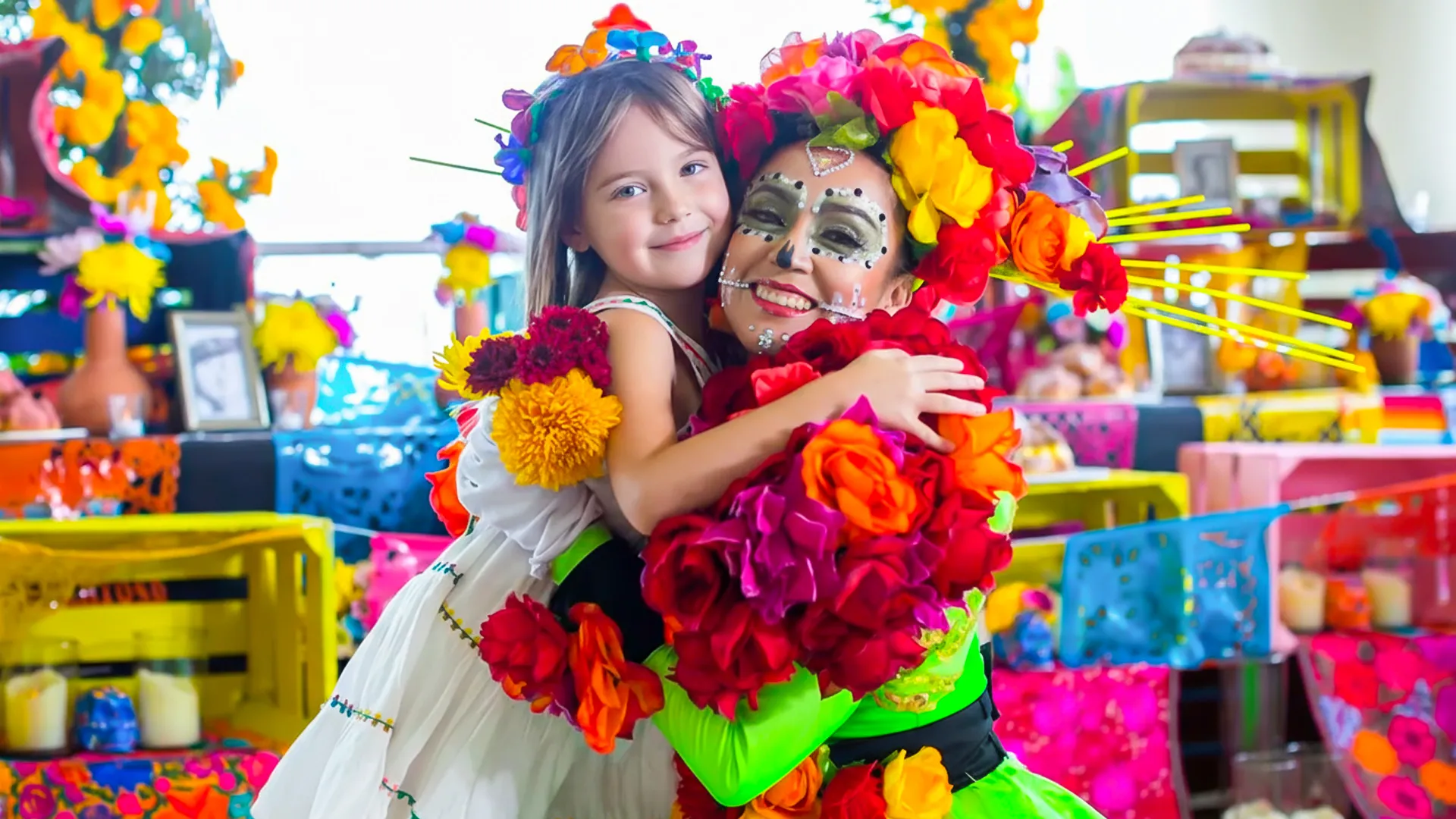 A person in colorful traditional attire hugging a child dressed in white, surrounded by vibrant Day of the Dead decorations at Hyatt Ziva Cancun.