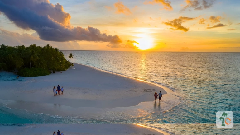 A couple and a family walk along a serene, sunlit beach at sunset, with golden skies and gentle waves.