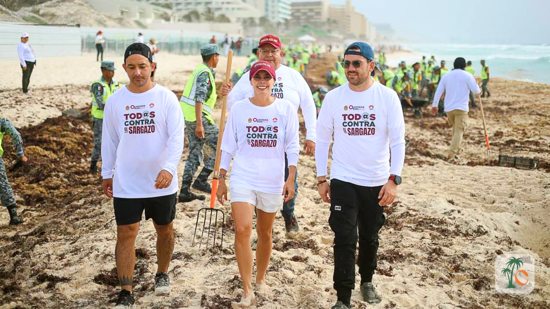 Local government officials and volunteers walking on a Cancun beach with tools, actively participating in sargassum seaweed removal.